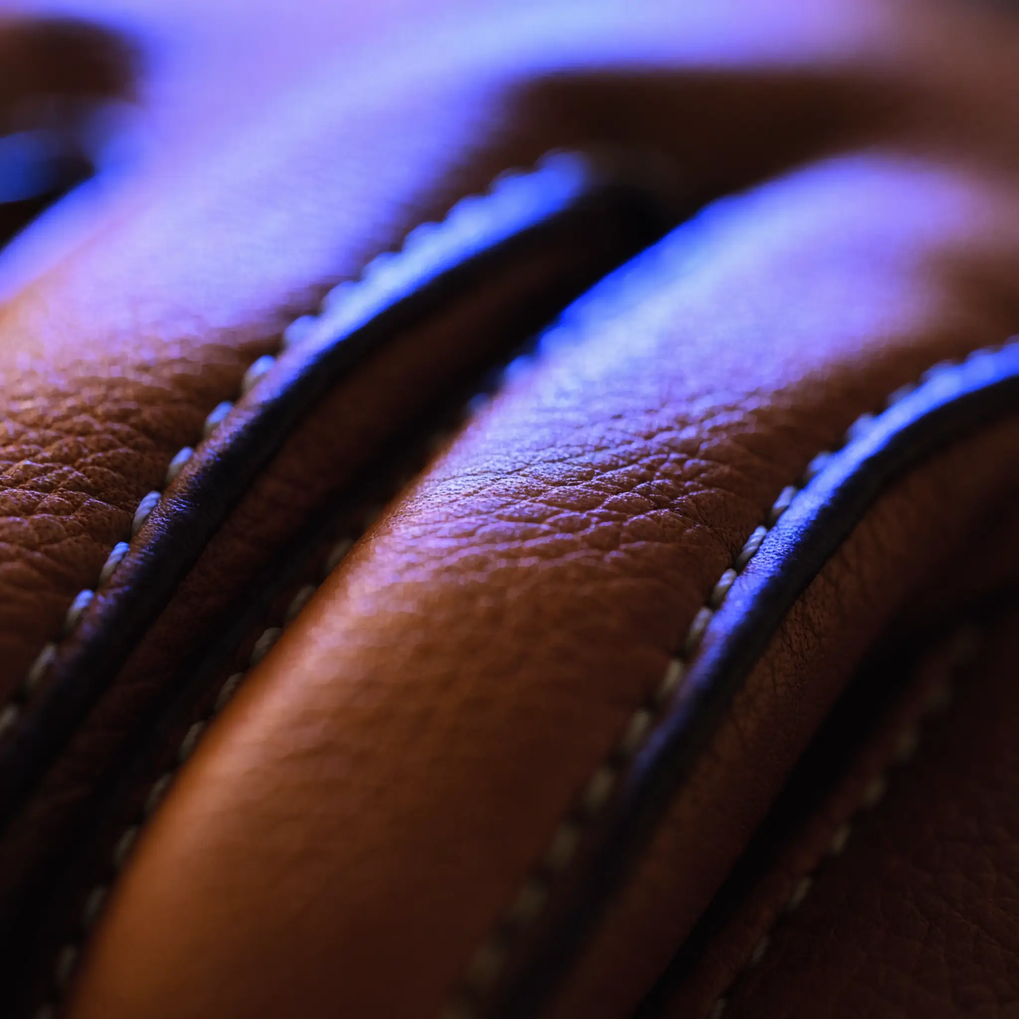 Macro of premium leather glove stitching under cool blue light